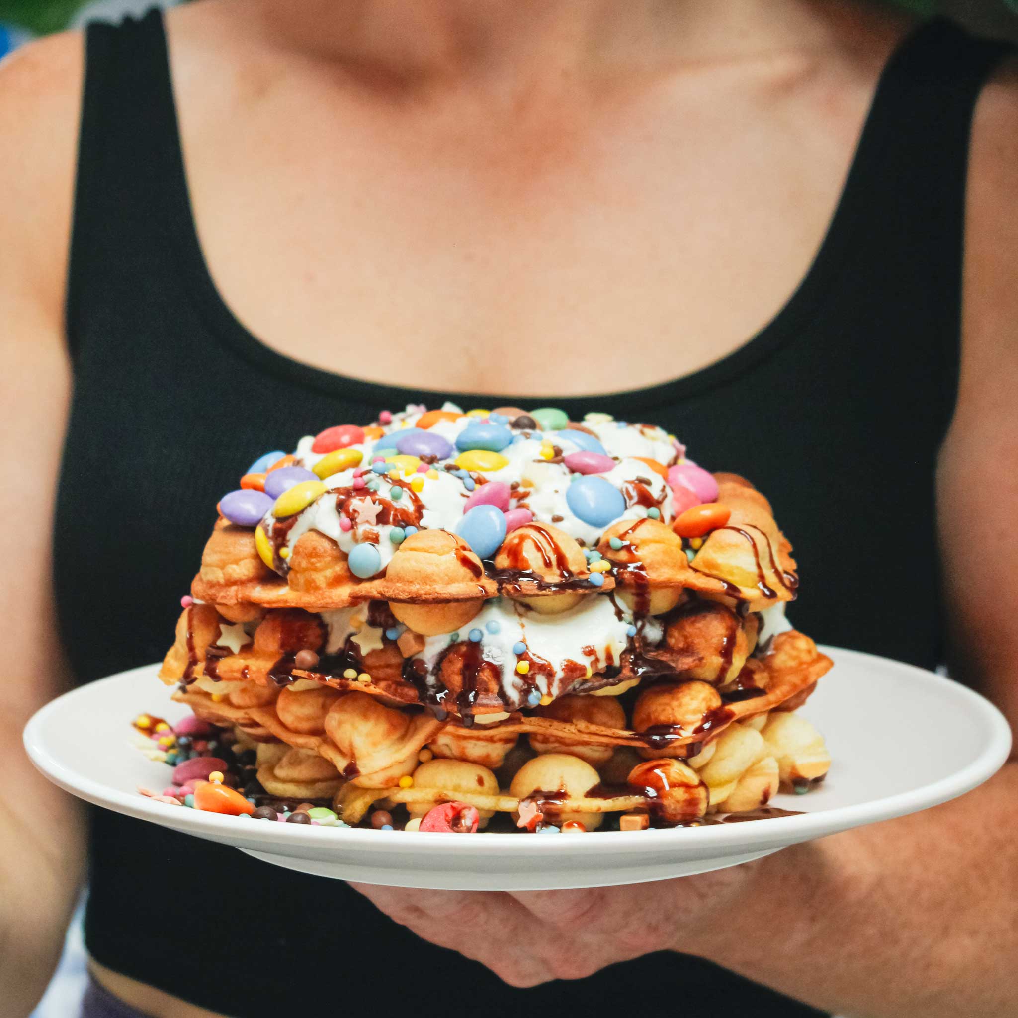 Bubble waffle stack covered in smarties and chocolate sauce