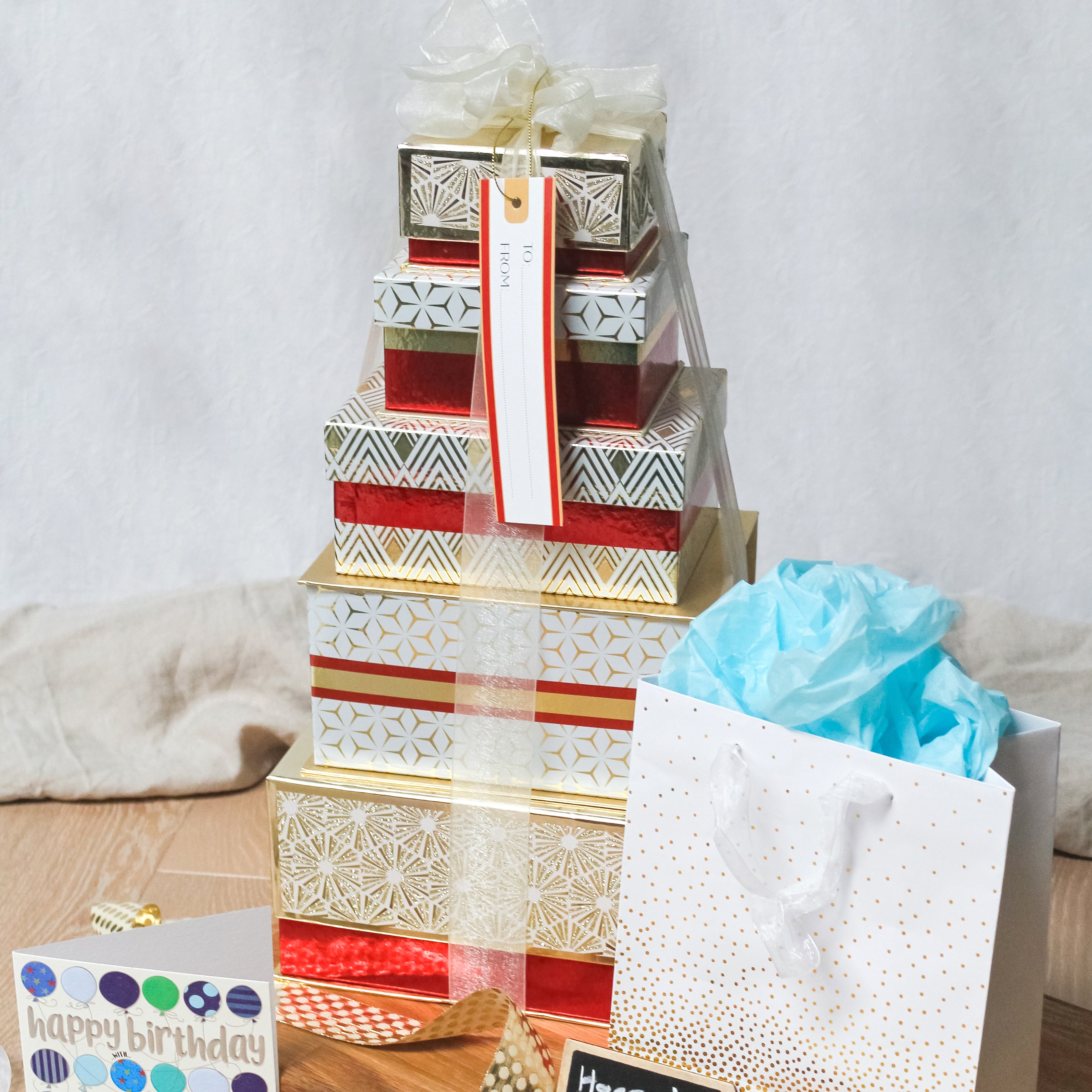 A red and gold box stack on a table with other presents