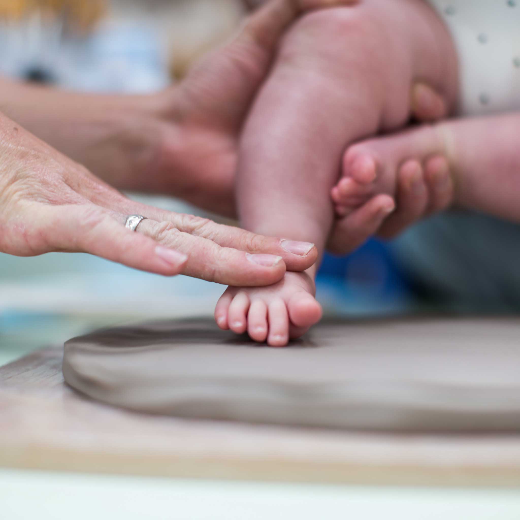 Baby making foot impression in clay at China Blue